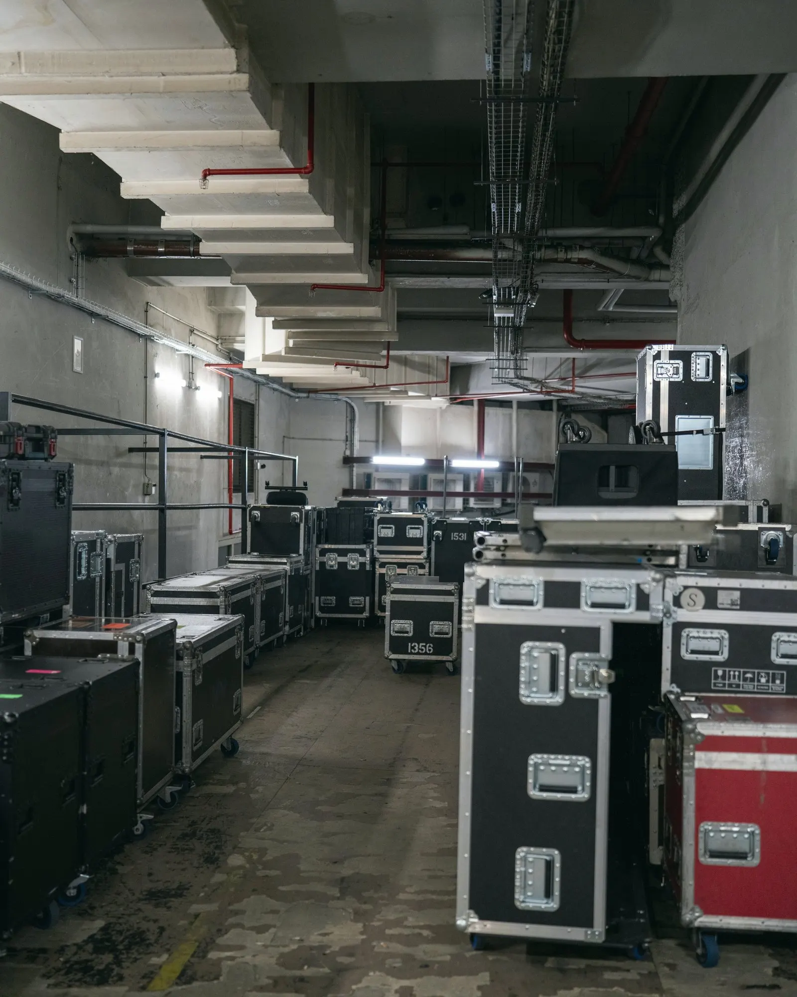 Ein Kellerflur voller Flightcases auf Rollen, dazwischen ein schmaler Gang