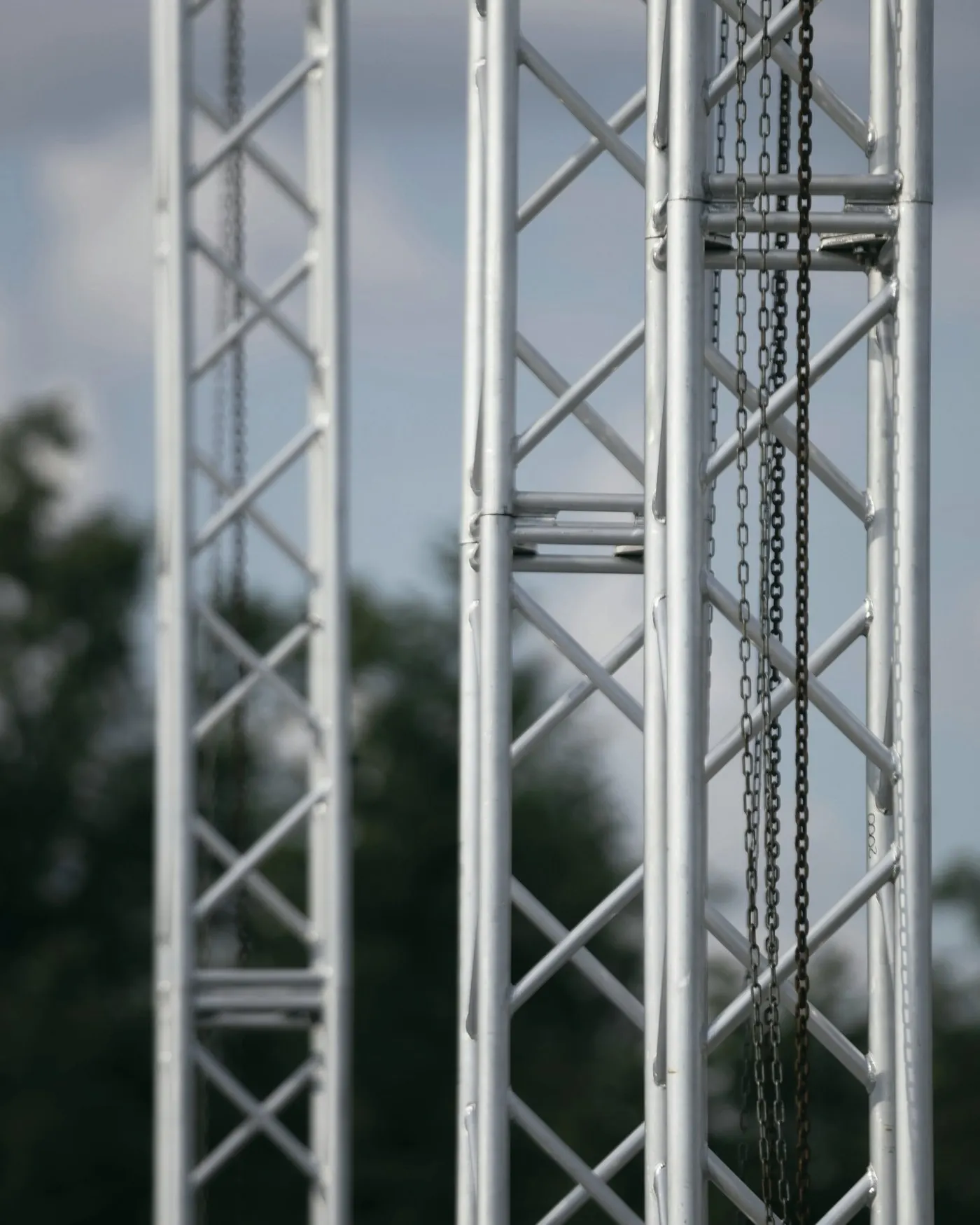 Truss-Türme aus Aluminium mit herabhängenden Kettenzügen vor bewölktem Himmel
